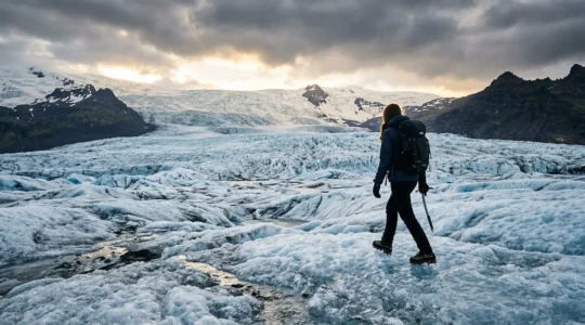 Randonneur avec crampons et piolet progressant sur glacier islandais sous lumiere arctique