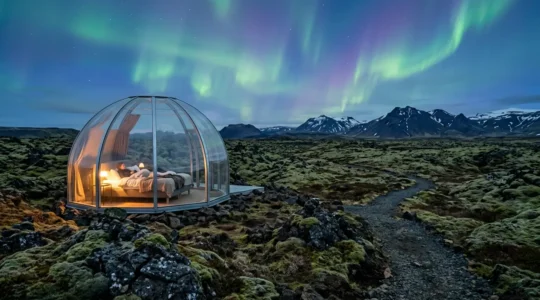 Vue intérieure d'une bulle transparente en Islande sous les aurores boréales avec paysage volcanique