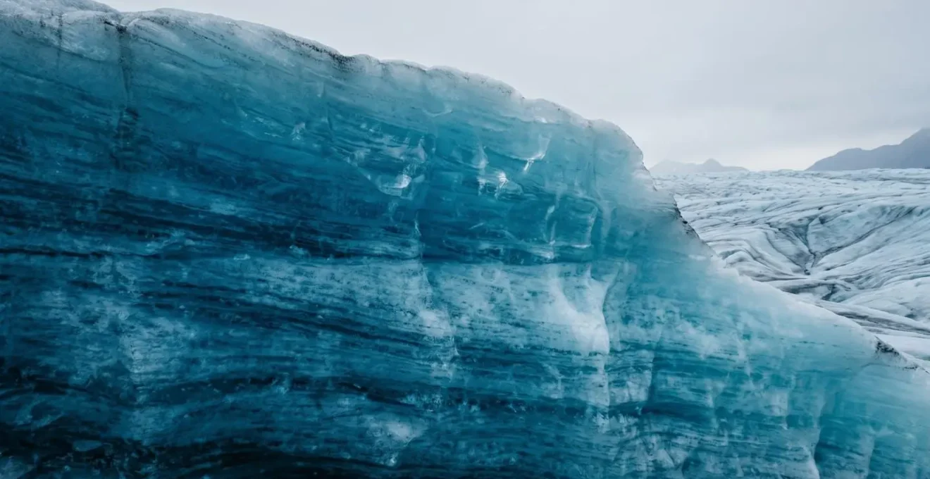 Paroi de glace bleue dense révélant des textures stratifiées et une translucidité cristalline