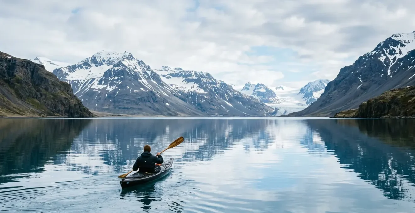 Kayakiste pagayant sur les eaux calmes d'un fjord islandais entouré de montagnes majestueuses