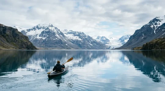 Kayakiste pagayant sur les eaux calmes d'un fjord islandais entouré de montagnes majestueuses