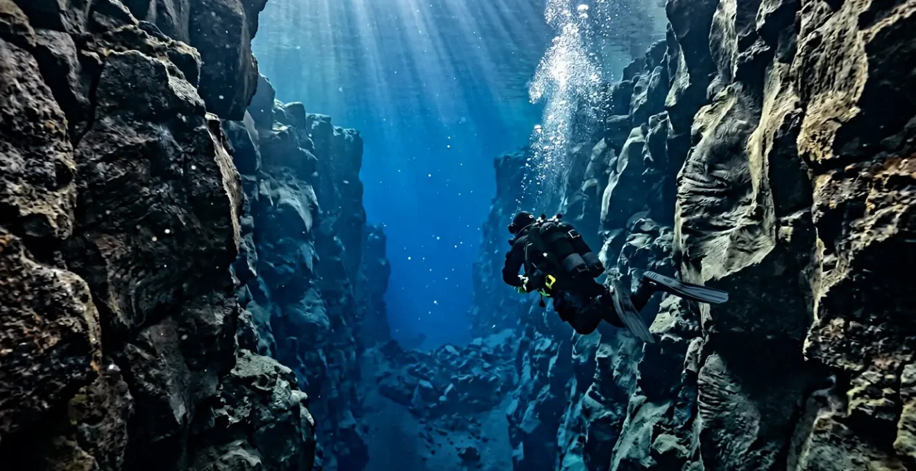 Plongeur dans une combinaison étanche naviguant entre les parois rocheuses d'une faille sous-marine cristalline en Islande
