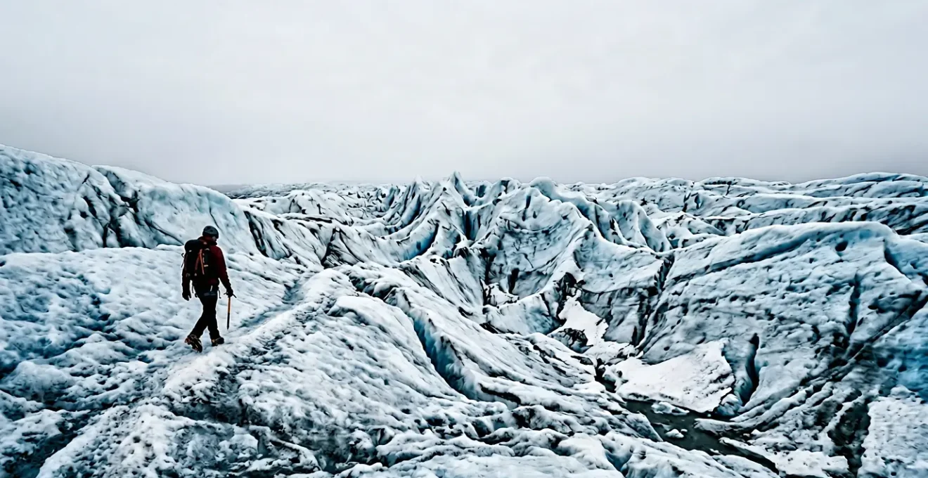 Randonneur équipé de crampons progressant sur un glacier islandais sous un ciel lumineux