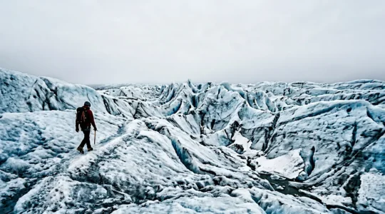 Randonneur équipé de crampons progressant sur un glacier islandais sous un ciel lumineux