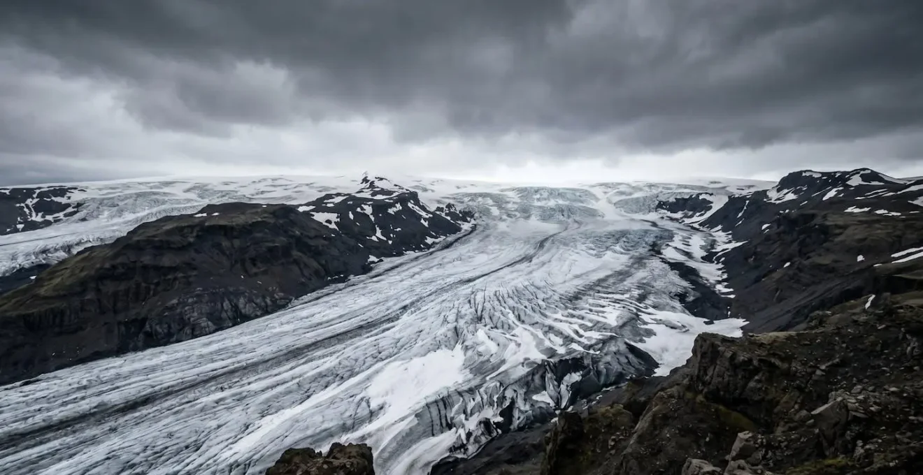 Vue grand-angle d'un glacier islandais sous ciel dramatique montrant les conditions météorologiques changeantes
